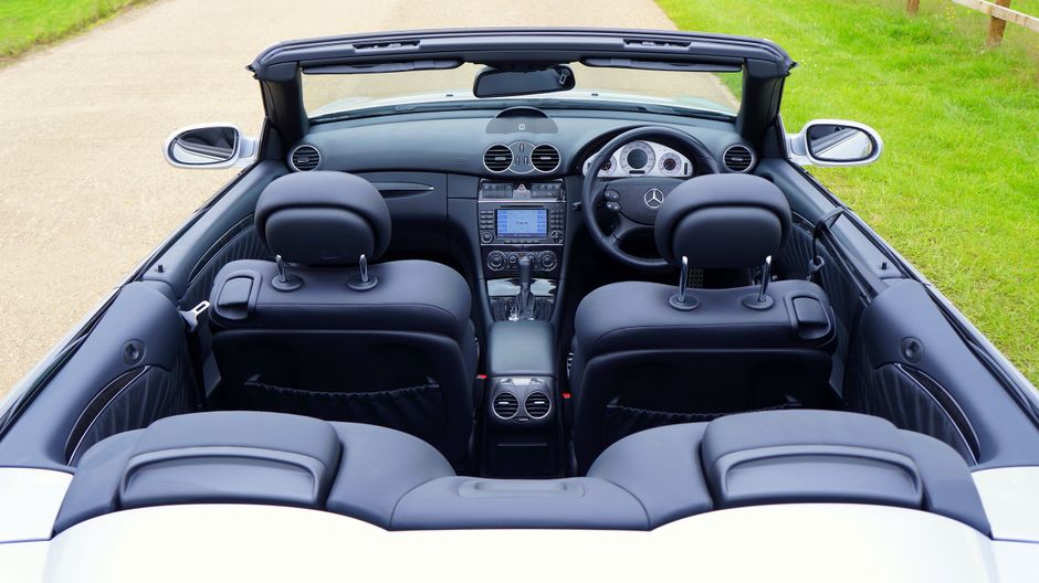 Close-up view of a car's front passenger seat and center console, both upholstered in light gray leather. The leather surface appears clean and well-maintained, with minimal creases and no visible sta